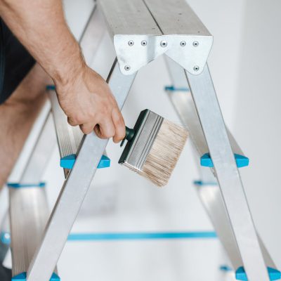 Painter with brush climbing ladder during renovation work